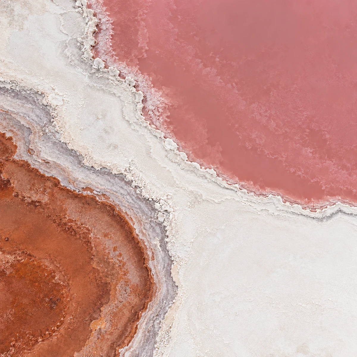 Aerial view of rose-coloured salt water, ivory mineral edges and terracotta ground